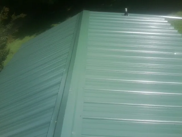 New green metal panels meeting at the ridge of a roof — Flat Roof Repair work by our crew in King And Queen Court House