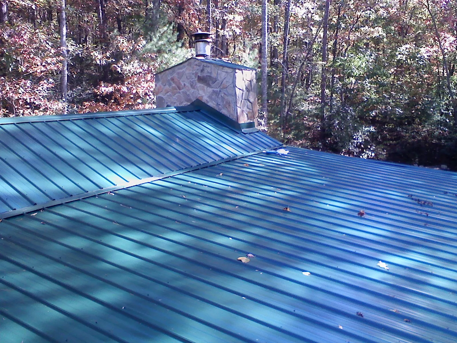 New green metal roof and stone chimney surrounded by autumn woods in King And Queen Court House