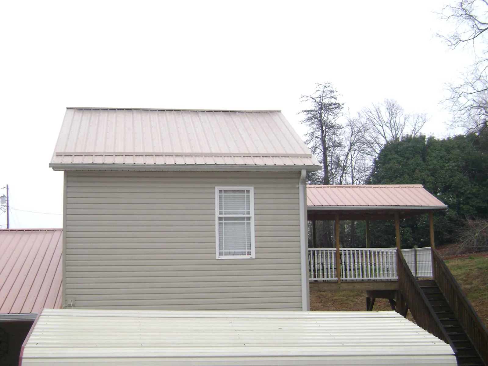 Tan metal roofs on a two story addition and attached porch, from a Roof Replacement job in King And Queen Court House