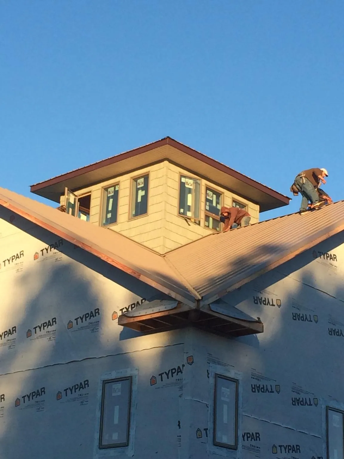 Roofers working around a rooftop cupola on a new metal roof at sunset — Roof Waterproofing in King And Queen Court House by Roofing Brothers
